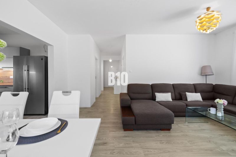 1 255 m² a 9 izieb I Priamo pri prírodnej rezervácii Šúr, len 15 minút - Obývacia izba s hnedou sedačkou, skleneným stolíkom a podlahou s dreveným dekorom v rodinnom dome.