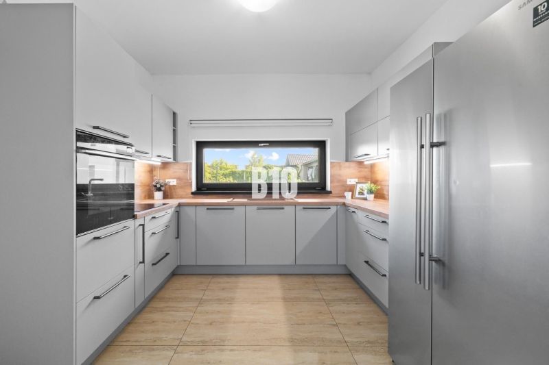 1 255 m² a 9 izieb I Priamo pri prírodnej rezervácii Šúr, len 15 minút - Kuchyňa s podlahou s dreveným dekorom, modernými spotrebičmi a veľkým oknom v rodinnom dome.
