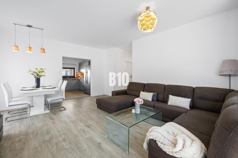 1 255 m² a 9 izieb I Priamo pri prírodnej rezervácii Šúr, len 15 minút - Obývacia izba v Rodinnom dome s pohovkou a jedálenským stolom, podlaha s dreveným dekorom.