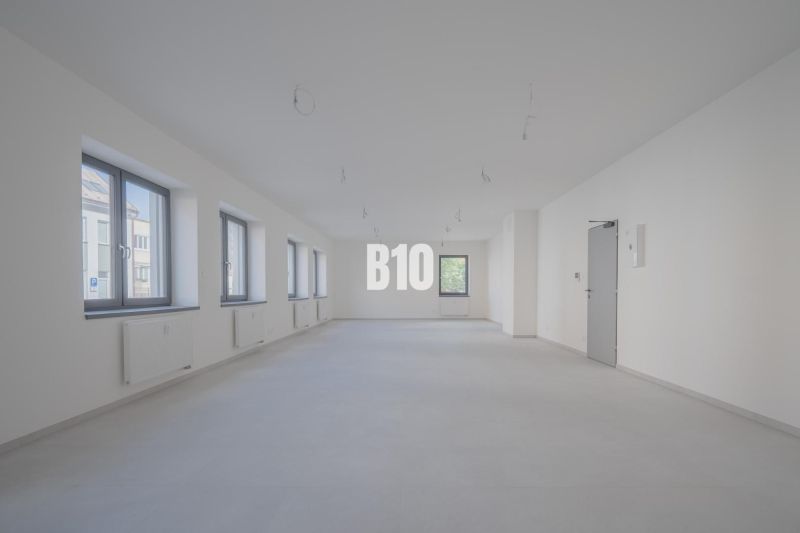 ADMINISTRATÍVNY PRIESTOR (127,87 m²) V NOVOSTAVBE REZIDENCIA KUBÍN V C - Priestranné kancelárie s viacerými oknami a závesnými svietidlami, biela podlaha.