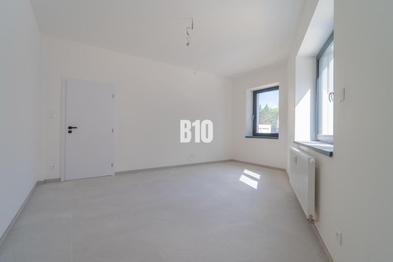 ADMINISTRATÍVNY PRIESTOR (127,87 m²) V NOVOSTAVBE REZIDENCIA KUBÍN V C - V Kancelárii s bielymi stenami a radiátorom pri okne preniká svetlo skrz okno.
