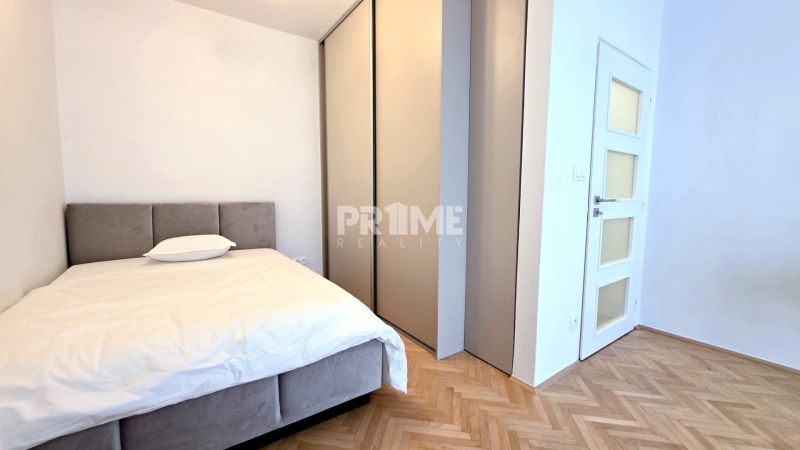 BÝVAJ PRVÝ v 1i BYTE, NOVÁ REKONŠTRUKCIA, BALKÓN, KLÍMA, Račianska ul. - Svetlá spálňa v 1-izbovom byte s podlahou s dreveným dekorom, posteľou a vstavanou skriňou.