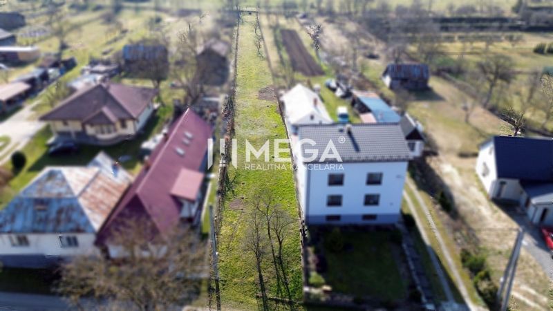 Rovinatý pozemok na predaj, obec Ptičie! Exkluzívna ponuka! - Pohľad na úzku parcelu na bývanie v Ptičom na ulici Ptičie, obklopenú domami.