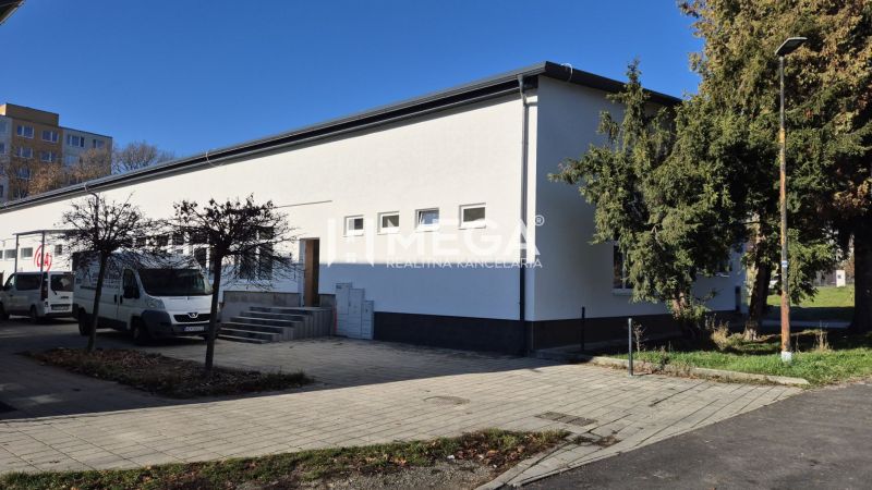 PREDAJ OBCHODNÉHO PRIESTORU v HUMENNOM (sídlisko 2A) - Obchodné priestory na ulici Tyršová v Humennom s bielou fasádou a stromami v okolí.