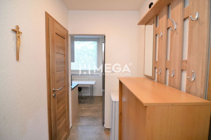 NOVÁ CENA-PREDAJ ZREKONŠTRUOVANÉHO 2-IZBOVÉHO BYTU (50 m2) S LODŽIOU H - Interiér 2-izbového bytu s nábytkom z dreveného dekoru a vešiakom pri vstupe.