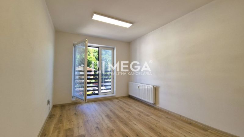 PRENÁJOM kancelárie blízko centra Humenného (15,20 m2) - Kancelária s veľkým oknom, podlahou s dreveným dekorom a radiátorom.