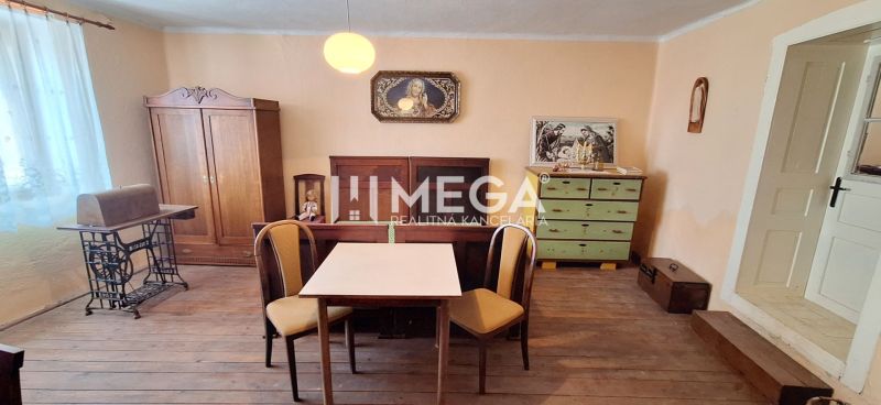 ZNÍŽENÁ CENA -  NA PREDAJ Dom v obci Kochanovce - Izba v rodinnom dome s podlahou s dreveným dekorom, stolom, stoličkami a starožitným nábytkom.