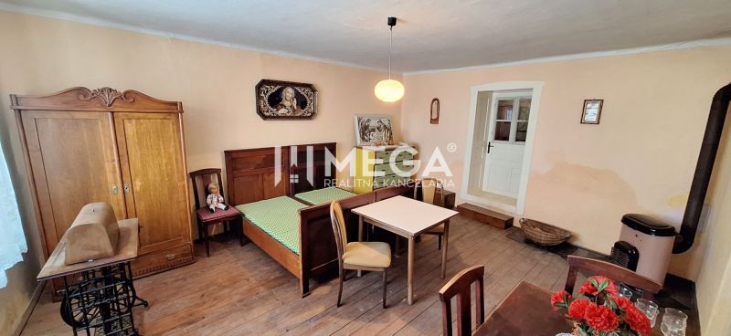 ZNÍŽENÁ CENA -  NA PREDAJ Dom v obci Kochanovce - Izba v rodinnom dome s posteľou, nábytkom a podlahou s dreveným dekorom.
