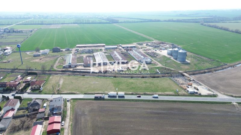 NA PREDAJ EXKLUZÍVNE: Lukratívny pozemok 6 086m2 – Hriadky (okres TV)  - Letecký pohľad na výrobné priestory v Hriadkach obklopené poľami a komunikáciou.