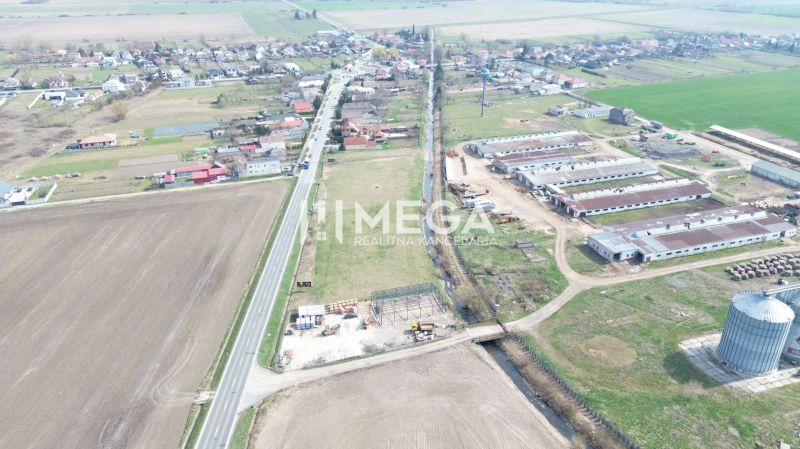 NA PREDAJ EXKLUZÍVNE: Lukratívny pozemok 6 086m2 – Hriadky (okres TV)  - Letecký pohľad na výrobné priestory v obci Hriadky obklopené poľnohospodárskymi políčkami a cestou.