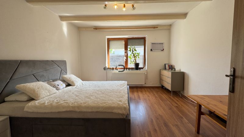 NA PREDAJ rodinný dom vo Svätoplukove - Spálňa v rodinnom dome s drevenou podlahou, posteľou a komodou.