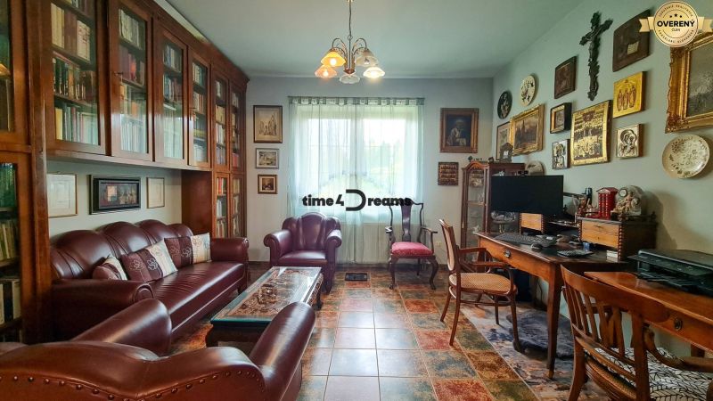 PREDAJ Rodinného domu na 70á pozemku v Ivanke pri Nitre - Obývačka na ulici Gergelova v rodinnom dome: kožená sedačka, knihovňa, dekoratívne obrazy na stenách.