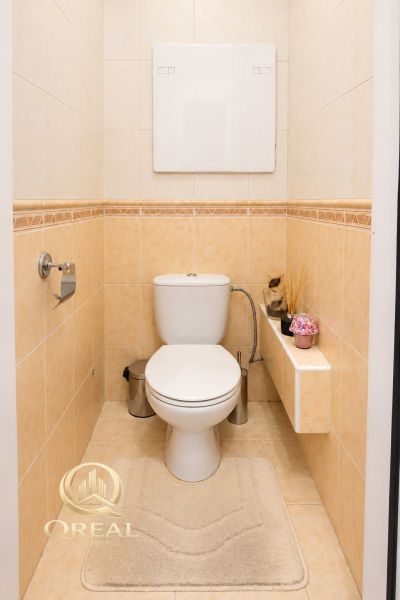 **QREAL**Moderné bývanie bez starostí**Len sa nasťahovať** - Toaleta s príslušenstvom v 2-izbovom byte, béžové obklady a podlaha.
