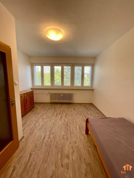 PRENÁJOM - 3-izbový byt priamo v centre Nitry s parkovaním a balkónom - Izba s podlahou s dreveným dekorom a jednoduchým nábytkom v 3-izbovom byte.