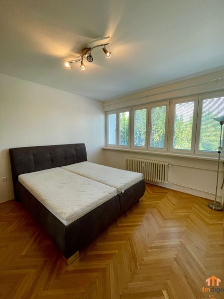 PRENÁJOM - 3-izbový byt priamo v centre Nitry s parkovaním a balkónom - Spálňa s veľkou posteľou a podlahou s dreveným dekorom v 3-izbovom byte.
