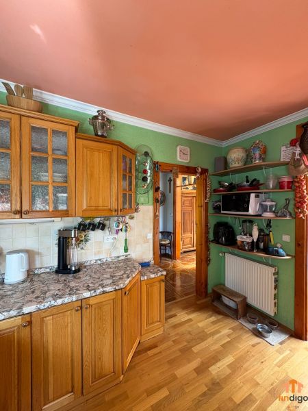PREDAJ - 4-izbový luxusný rodinný dom s investičným pozemkom  - Kuchyňa v rodinnom dome s dreveným dekorom podlahy, skriňami a pastelovými stenami.