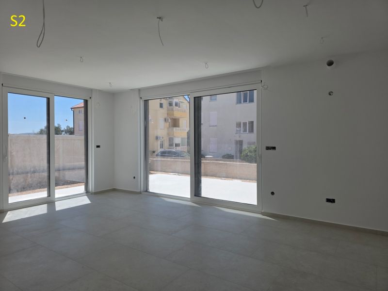 CHORVÁTSKO - Moderné apartmány 80 m od mora - SRIMA, VODICE - Svetlý interiér 3-izbového bytu s veľkými oknami a dlažbou.