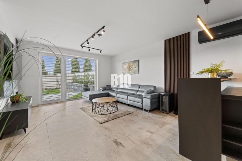 Moderný 4i dom v RED OAK, Lužianky | Kompletné zariadenie! - Obývacia izba s koženou sedačkou a oknami na terasu v rodinnom dome.