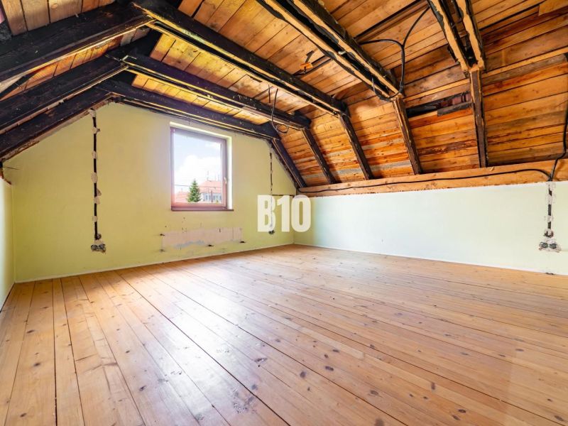 REZERVOVANÉ_RD v Nitre, Veľké Janíkovce – 994 m2 pozemok - Podkrovie rodinného domu s podlahou s dreveným dekorom a strešnými trámami.