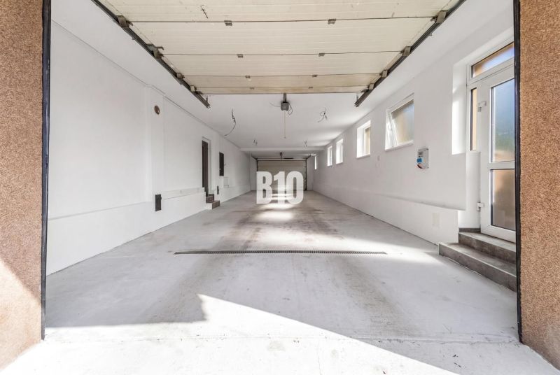 4i rodinný dom Lehota | 230 m² | Bazén | 85 m² garáž | 5 min. od Nitry - Priestranná garáž v rodinnom dome v meste Nitra s viacerými oknami a bielymi stenami.