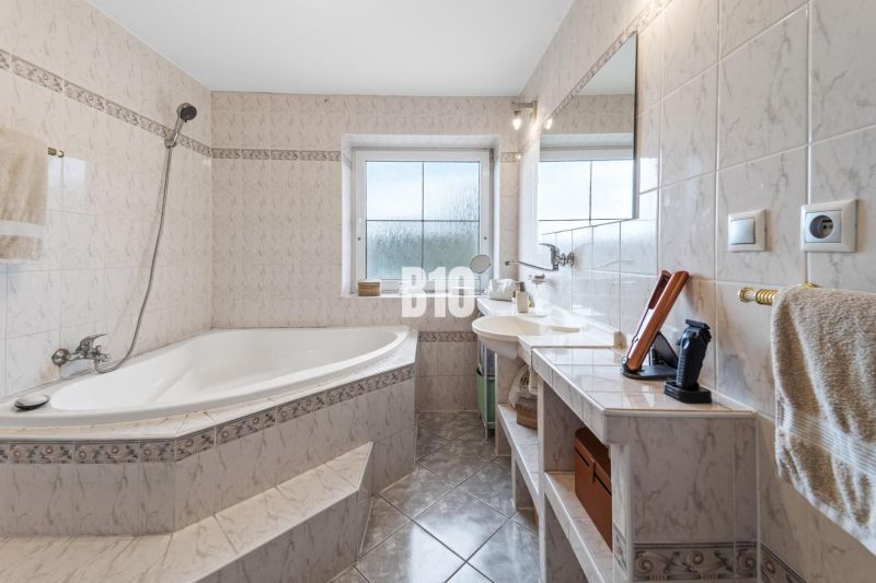 4i rodinný dom Lehota | 230 m² | Bazén | 85 m² garáž | 5 min. od Nitry - Kúpeľňa v rodinnom dome s rohovou vaňou a oknom, svetlé obklady.