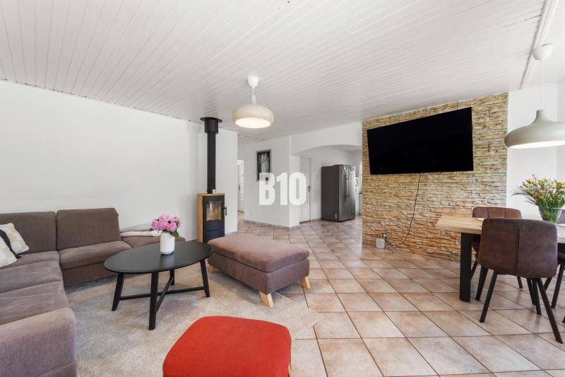 4i rodinný dom Lehota | 230 m² | Bazén | 85 m² garáž | 5 min. od Nitry - Obývacia izba v rodinnom dome s krbom a televízorom na kamennem obklade steny.