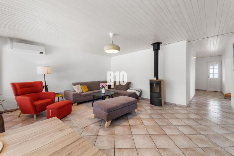 4i rodinný dom Lehota | 230 m² | Bazén | 85 m² garáž | 5 min. od Nitry - Obývacia izba v rodinnom dome s krbom, červeným kreslom a šedou sedačkou.