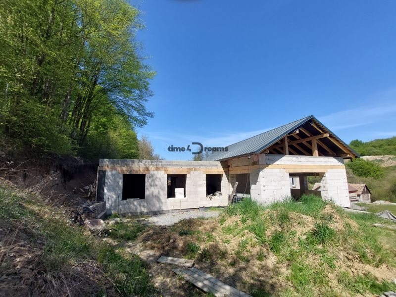 NA PREDAJ rozostavaný 5-izbový rodinný dom   - Stavba rodinného domu vo Zvolene, obklopená lesom a prírodou, pod modrou oblohou.