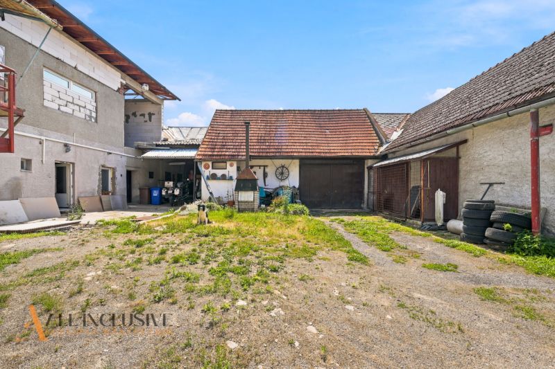 Na predaj 5-izb. dvojgen. rodinný dom, Dúbravica - Dvor rodinného domu v Dúbravici s hospodárskymi budovami a psom na pozemku.