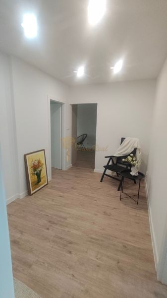 Novozrekonštruovaný 4-izb. byt, Exnárova ul., Ružinov - Pošeň - Interiér 4-izbového bytu s podlahou s dreveným dekorom, kreslom a obrazom.