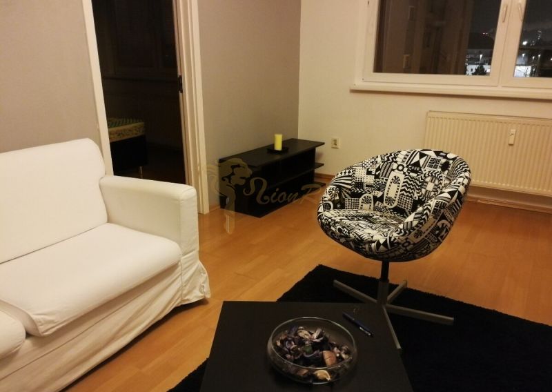2-izb. byt na ul. Bodrocká, Podunajské Biskupice - Obývacia izba s bielym kreslom a stoličkou, podlaha s dreveným dekorom.