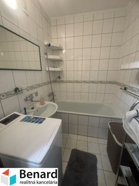 Na prenájom útulný 1,5-izbový byt na Okružnej ulici - Kúpeľňa v 2-izbovom byte s vaňou, umývadlom a práčkou, obložená bielymi dlaždicami.