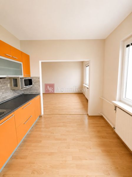 Predaj! slnečný 3-izbový byt s loggiou 74 m² Podbreziny - LM - Kuchyňa a obývacia izba s oranžovou linkou v 3-izbovom byte, podlaha s dreveným dekorom.