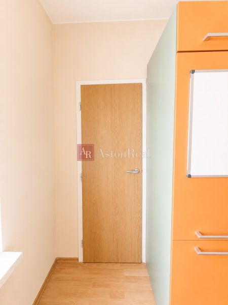 Predaj! slnečný 3-izbový byt s loggiou 74 m² Podbreziny - LM - Dvere a oranžová kuchynská linka v 3-izbovom byte s podlahou s dreveným dekorom.