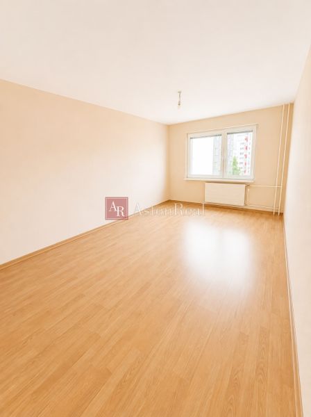 Predaj! slnečný 3-izbový byt s loggiou 74 m² Podbreziny - LM - Priestranná izba s oknom a podlahou s dreveným dekorom v 3-izbovom byte.