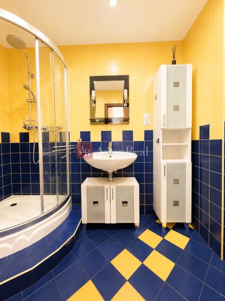 Predaj! slnečný 3-izbový byt s loggiou 74 m² Podbreziny - LM - Kúpeľňa v 3-izbovom byte s modro-žltými dlaždicami a sprchovým kútom.