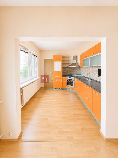 Predaj! slnečný 3-izbový byt s loggiou 74 m² Podbreziny - LM - Kuchyňa so vstavanými spotrebičmi, výrazným oranžovým nábytkom a podlahou s dreveným dekorom v 3-izbovom byte.
