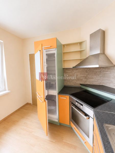 Predaj! slnečný 3-izbový byt s loggiou 74 m² Podbreziny - LM - Kuchyňa v 3-izbovom byte s podlahou s dreveným dekorom a farebnými skrinkami.