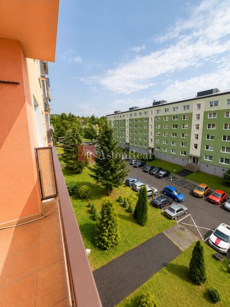 Predaj! slnečný 3-izbový byt s loggiou 74 m² Podbreziny - LM - Výhľad z balkóna na zeleň a parkovanie pri Brezovej ulici v Liptovskom Mikuláši.