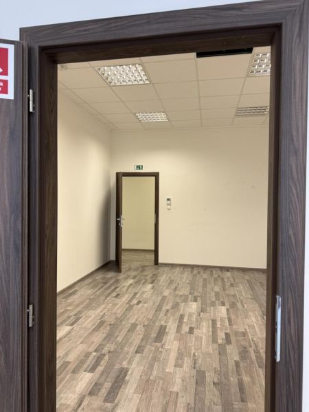 Kancelárske, obchodné a skladové priestory od 14m2 do 500m2 v areáli. - Prázdna miestnosť s bielymi stenami, stropnými svetlami a podlahou s dreveným dekorom.