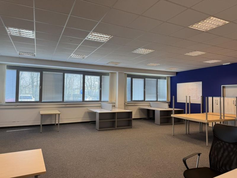 Kancelárske, obchodné a skladové priestory od 14m2 do 500m2 v areáli. - Kancelársky priestor s kobercovou podlahou, veľkými oknami a kancelárskym nábytkom v skladoch a halách.