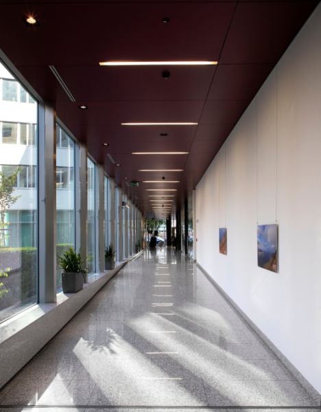 Moderné kancelárske a obchodné priestory v novostavbe v širšom centre - Dlhá presklená chodba na ulici Plynárenská, vedľa kancelárií so závesnými obrazmi na stene.