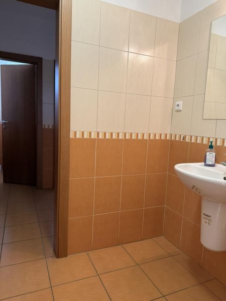 Kancelária 22m2 v menšej administratívnej budove v areáli pri Bozine. - Interiér kancelárie s keramickým obkladom a umývadlom, dvere vedú do ďalšej miestnosti.