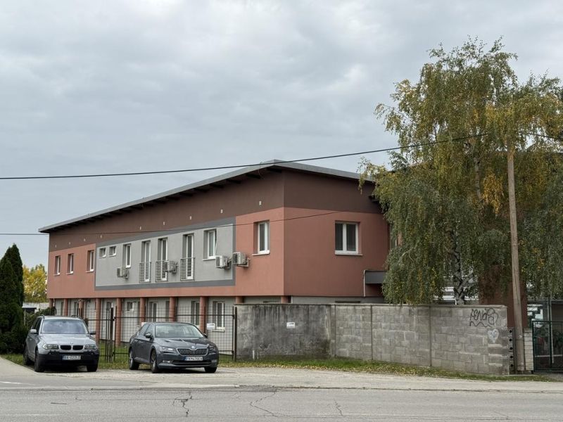 Kancelária 22m2 v menšej administratívnej budove v areáli pri Bozine. - Budova s kanceláriami na Šenkvickej ceste v Pezinku, oplotený areál, zaparkované autá.