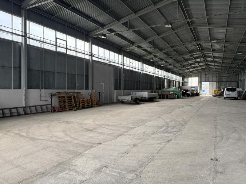 Sklad. priestory 200m2 - 1000m2, spevnené plochy do 6000m2 v areáli. - Interiér skladov a hál s betónovou podlahou a zaparkovanými vozidlami a prívesmi.