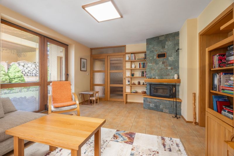 | Výnimočný rodinný dom s pozemkom 1516 m2 Nízke Tatry - Obývacia izba v rodinnom dome s krbom, policom a pohodlným kreslom.