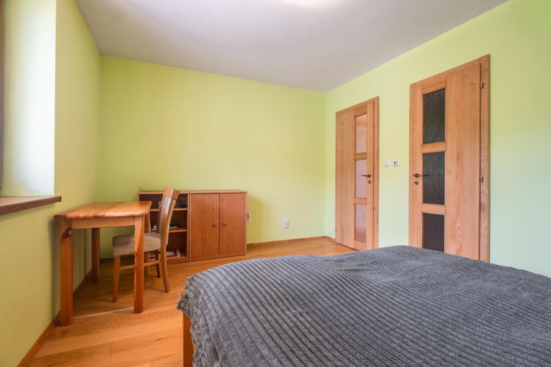 | Výnimočný rodinný dom s pozemkom 1516 m2 Nízke Tatry - Spálňa v Rodinnom dome s nábytkom z dreva a podlahou s dreveným dekorom.