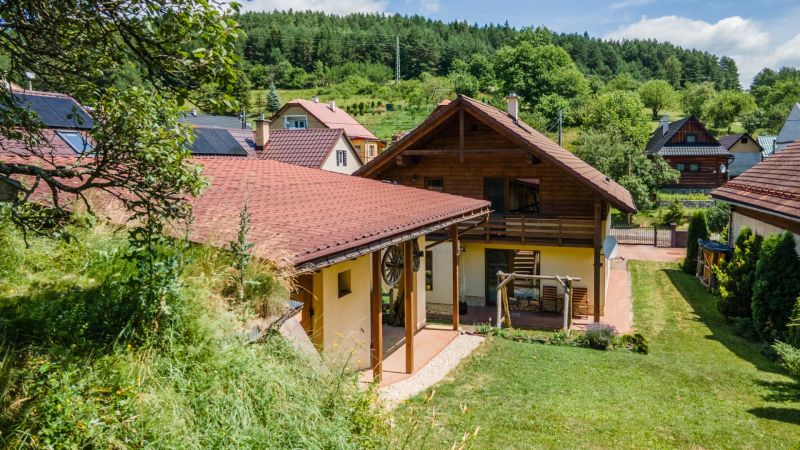 | Výnimočný rodinný dom s pozemkom 1516 m2 Nízke Tatry - Rodinný dom v Hornej Lehote s červenou strechou a okolitou zeleňou.