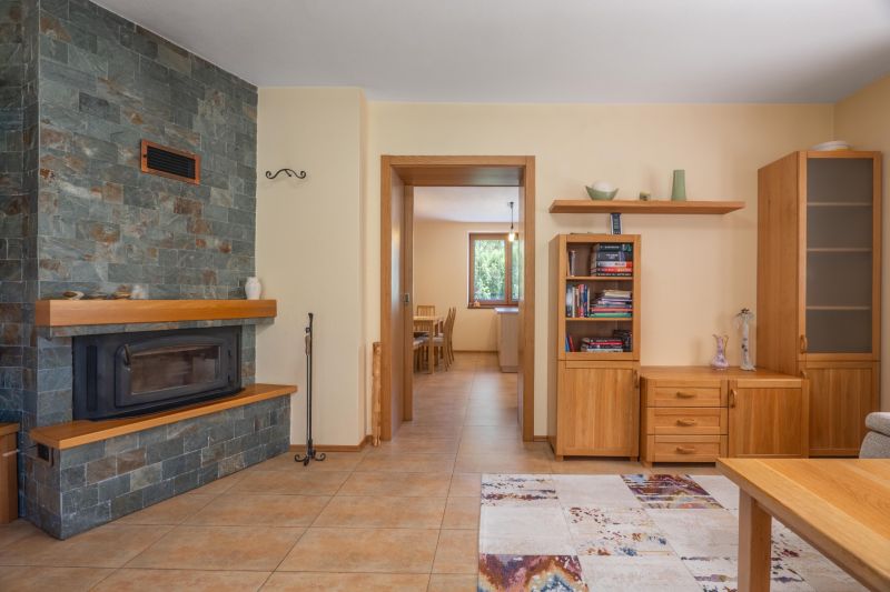 | Výnimočný rodinný dom s pozemkom 1516 m2 Nízke Tatry - Krb s kamenným obkladom v obývačke rodinného domu s dreveným nábytkom a dlažbou.