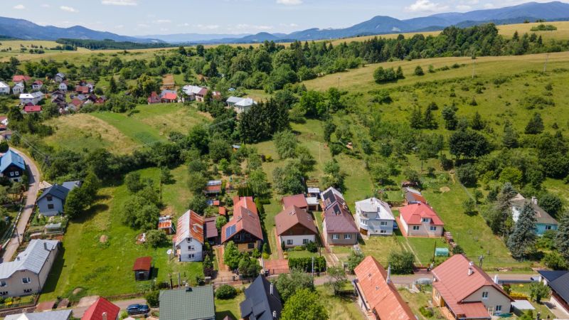 | Výnimočný rodinný dom s pozemkom 1516 m2 Nízke Tatry - Pohľad na rodinné domy v HorneJ Lehote s kopcovitou krajinou v pozadí.